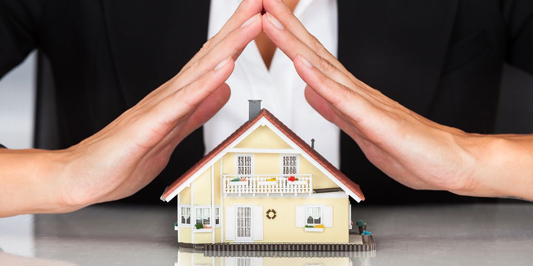 hands put together held over a small model house