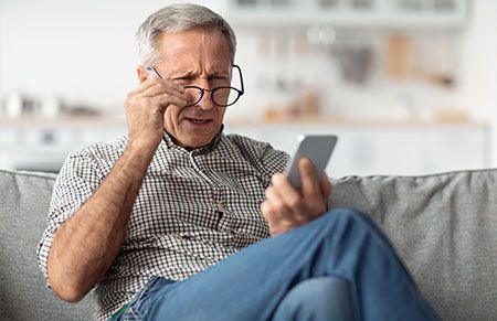 an older man looking at his phone shocked after learning about Medicaid estate recovery