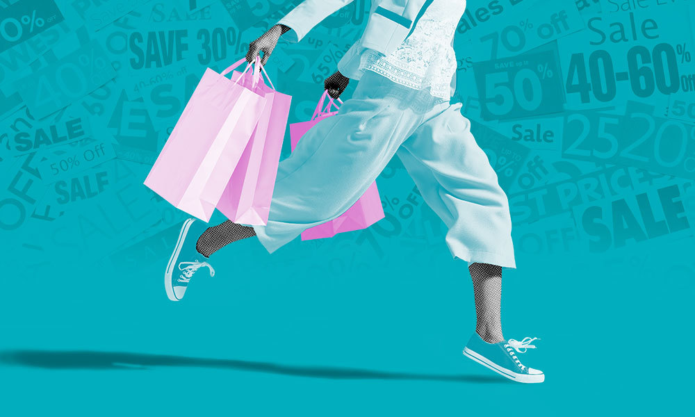 person walking carring lots of shopping bags with signs of 'sale' in the background