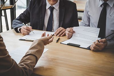 three people going over documents with paper and pen 