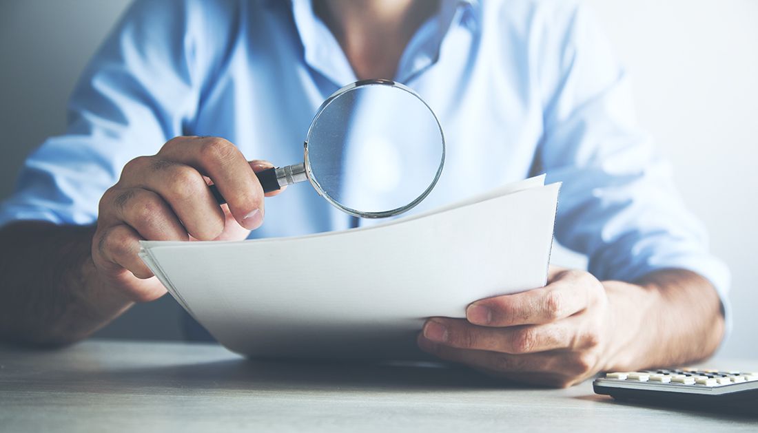 a person making sure they are not overlooking beneficiary designations with a magnifying glass