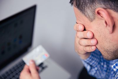 a disappointed man looking down at his credit card