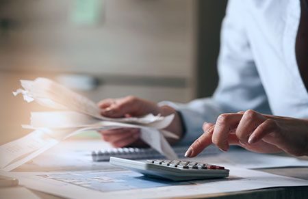 a business owner doing tax calulations while holding a stack of papers