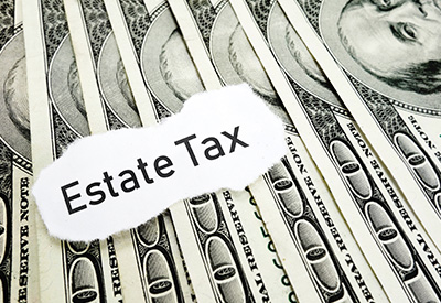 a label with Estate Tax on it lying on one hundred dollar bills