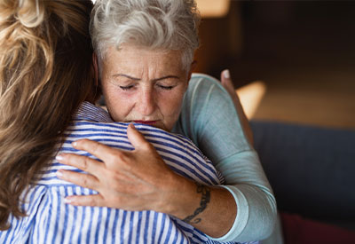 elderly woman visibly emotional being embraced by a younger woman after discussing her living will