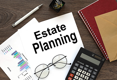 An estate planning document sits on a desk with a calculator, glasses, and charts, symbolizing organizing one's inheritance, ensuring liquidity, and securing college funding for beneficiaries.