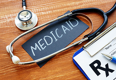 A stethoscope and an Rx prescription pad on a desk with a black card reading 'Medicaid,' concerning inheritance and its impact on benefits.