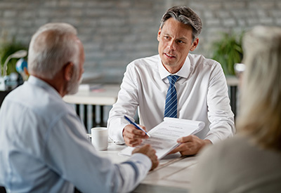 A professional reviewing estate planning documents with an elderly couple, discussing post-divorce powers of attorney.