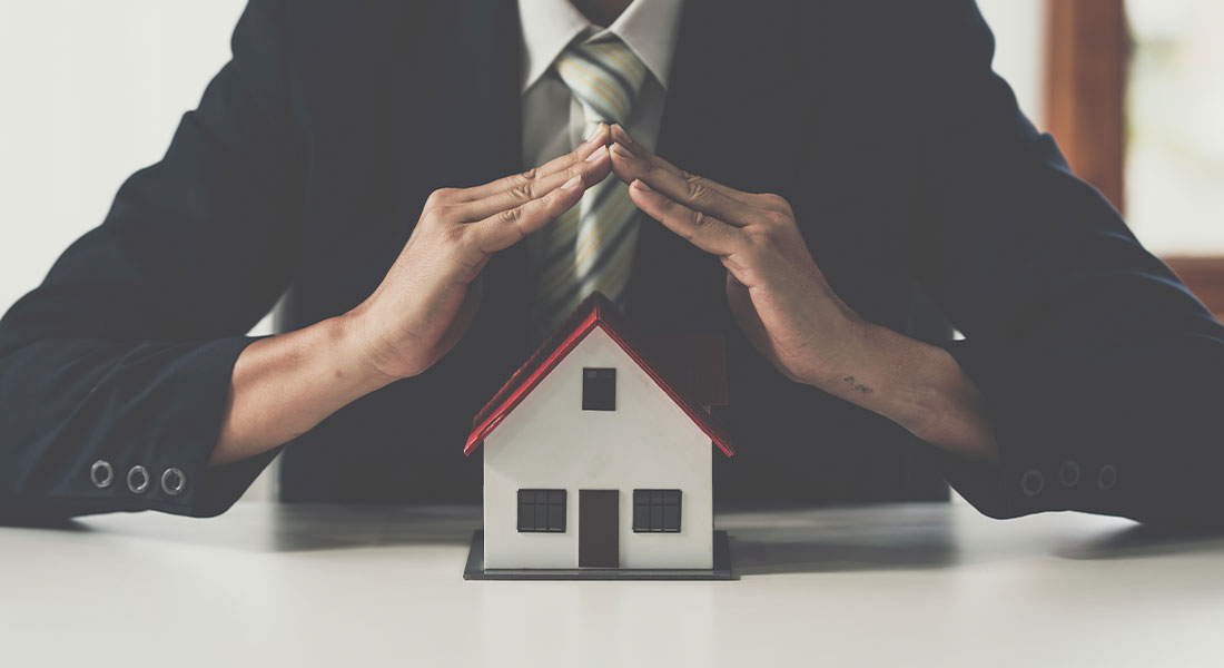 Someone holding their hands over a model home to symbolize safely storing estate documents