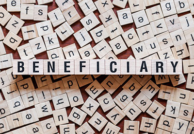 Scrabble tiles are scattered randomly, with tiles in the center forming the word 'BENEFICIARY'