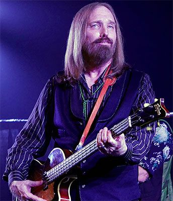 Tom Petty playing the guitar on stage