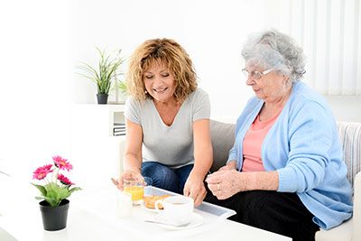 Guardians - Mother and daughter sitting on a couch with a tray of food