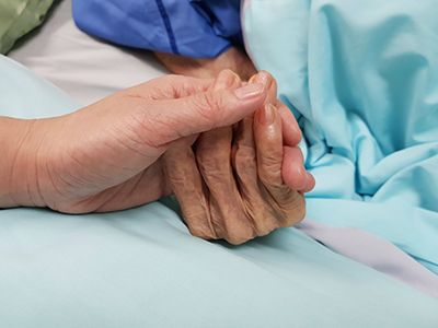 Healtcare Power of Attorney - Clode up of a younger person holding the hand of an older person in a hospital bed