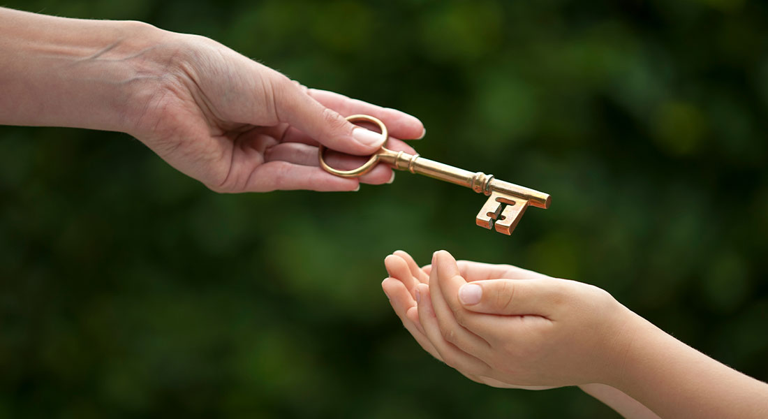 an adult handing over a key to a younger family member to represent an inheritance