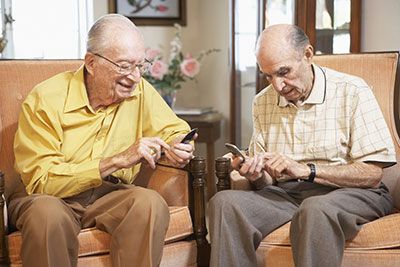 Health - Two senior men sitting in chairs texting