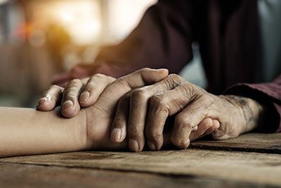 Health - Senior holding hands with a younger individual