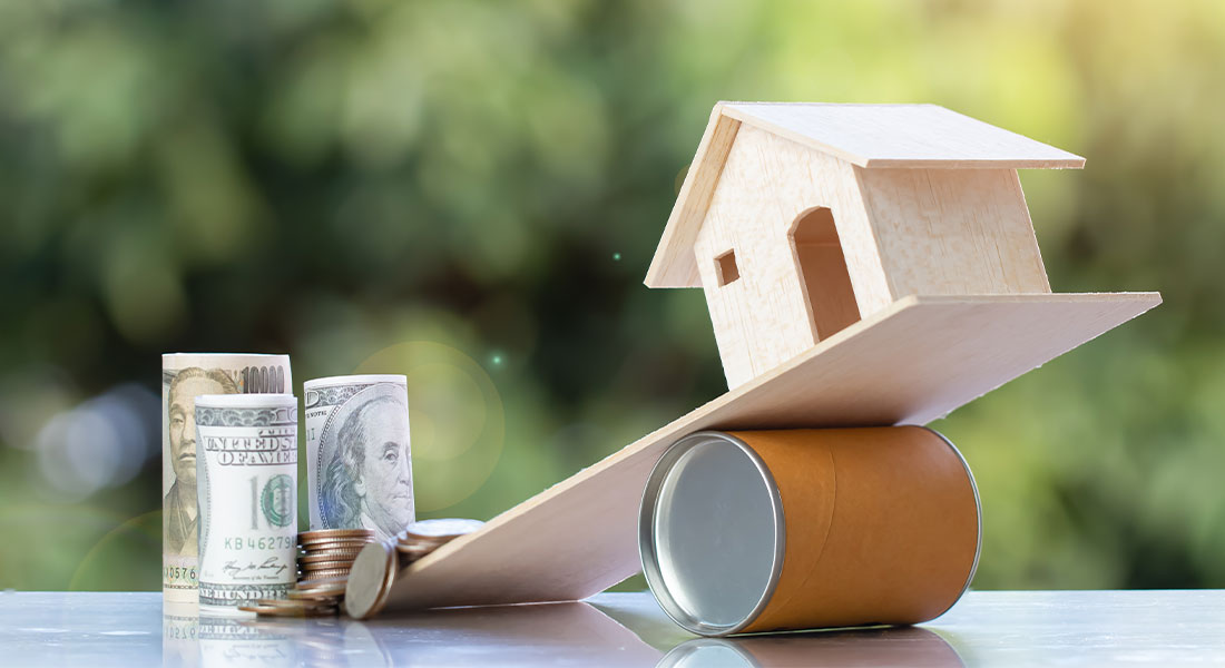 A model home being tipped over by dollars and coins to show that The Texas intestacy laws and Tennessee intestacy laws differ in the division of assets if one dies intestate, as common law states do not recognize community property.