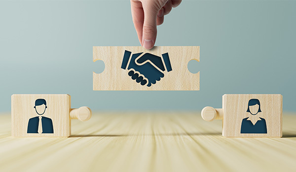 two blocks with a person on each and a wooden block to connect them labeled with a handshake