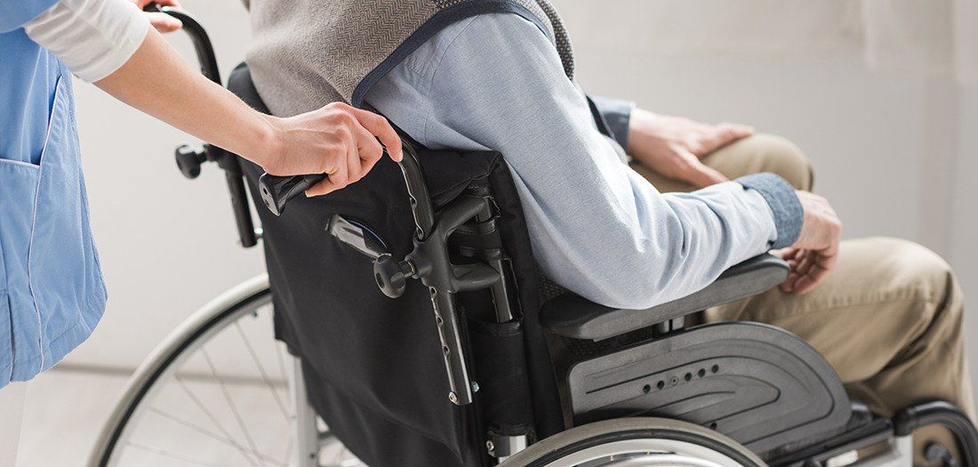 a caregiver pushing a senior with disabilities in a wheelchair