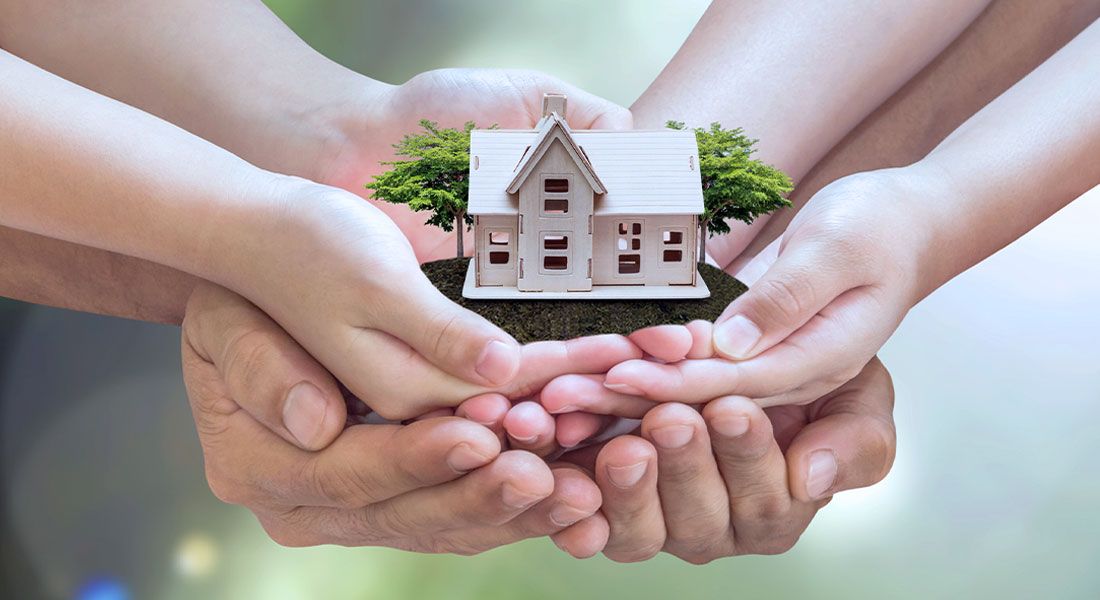 a group of hands holding a toy house to symbolize protection a loved ones inheritance