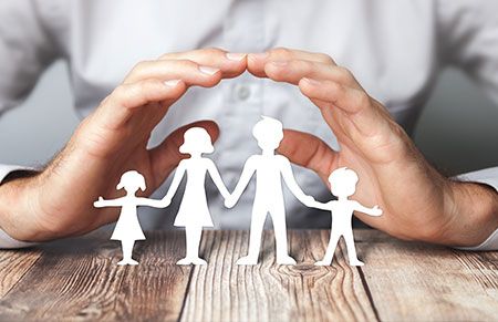 a pair of hands hovering over a family to protect them