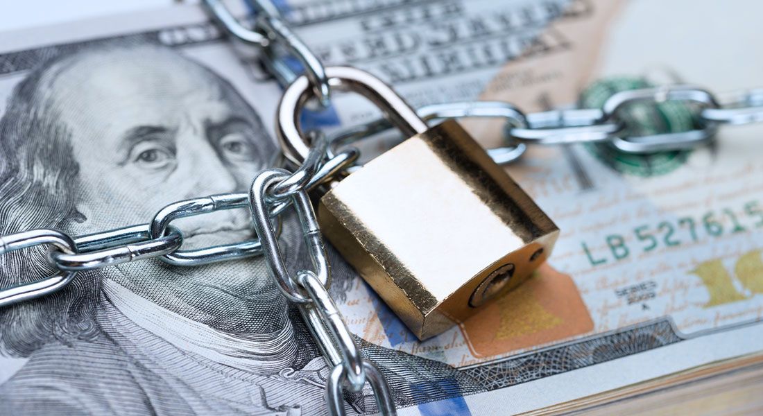 a one hundred dollar bill locked up with chains and lock