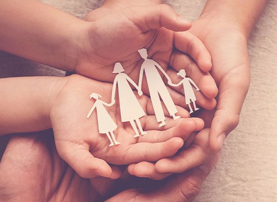 Hands holding a cut out paper family