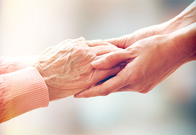 an older set of hands holding a younger set of hands