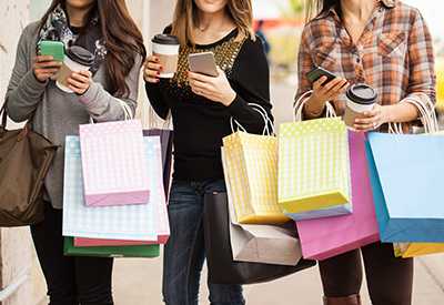 three women carrying shopping bags and drinking coffee