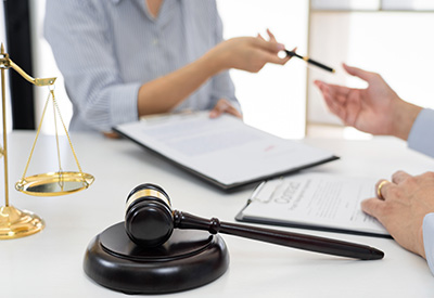 Two individuals engaged in a discussion at a table with a gavel and scales of justice, suggesting a legal consultation regarding business taxes.