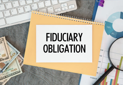 A notepad with "FIDUCIARY OBLIGATION" written on it, surrounded by financial documents and tools, emphasizing the responsibilities of a successor trustee.