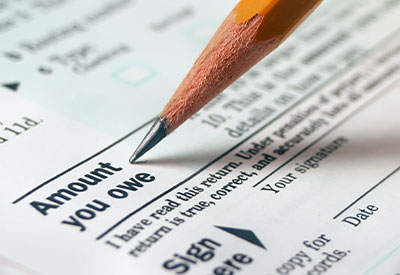 A pencil pointing to a section on a financial document labeled 'Amount you owe,' with small text and a signature line visible
