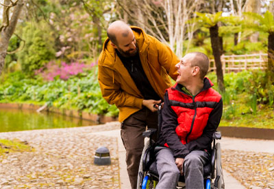 A caregiver assists a wheelchair user outdoors