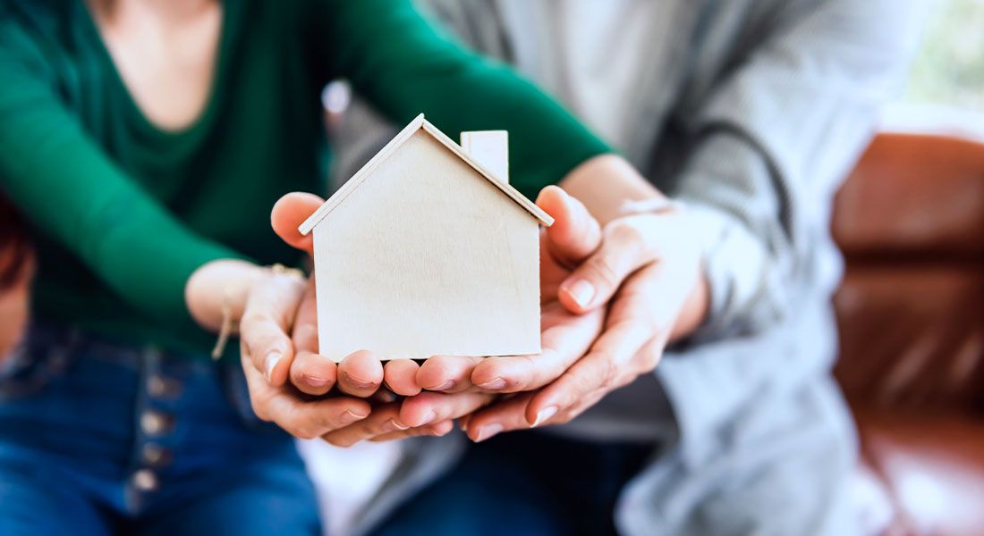 A couple holding up a wooden model house