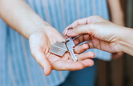Someone handing over a pair of keys to a property due to partition