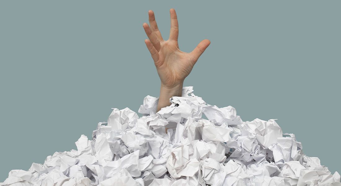 an arm coming out of a pile of estate planning documents to symbolizing letting the documents pile up due to procrastination