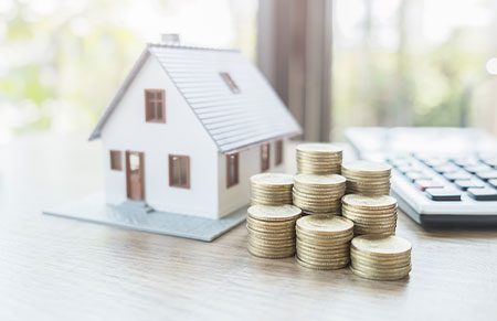 A stack of coins next to a toy home.