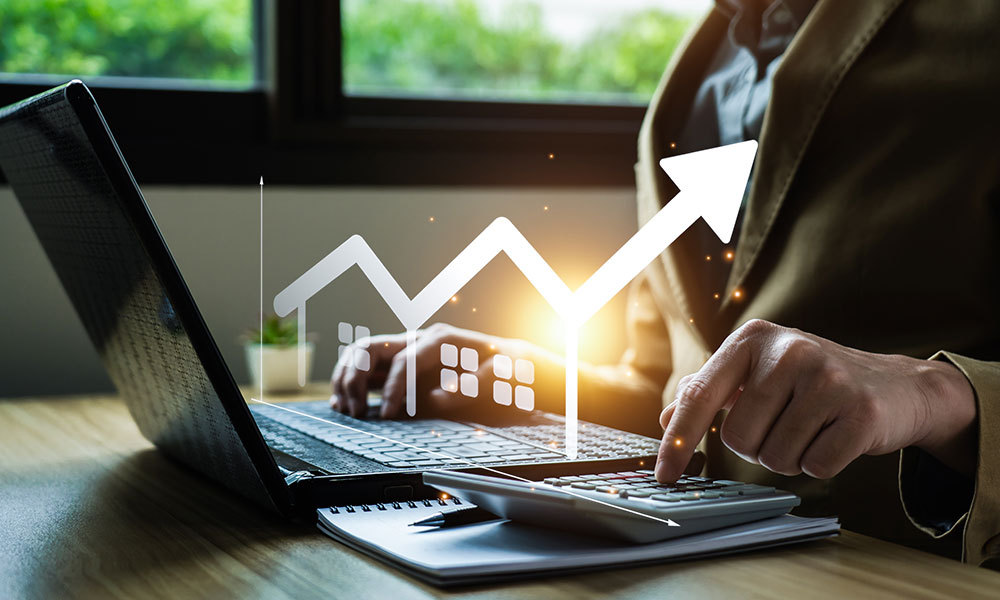 Person sitting at desk using a laptop and calculator