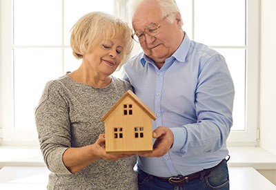elderly couple holding model home in hands together