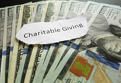 A pile of U.S. dollar bills with a label reading 'Charitable Giving,' representing the role of financial contributions in reducing tax liability through donations to charitable organizations in estate plans.