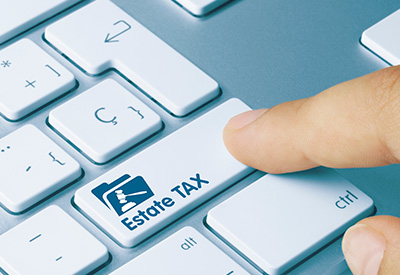 A finger pressing an 'Estate Tax' key on a keyboard.