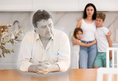A ghost-like figure of a man sits apart from his family, symbolizing financial hardship and the need for homestead protection to secure their primary residence.