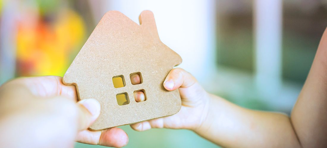 Parent and child holdin a wooden house cut-out