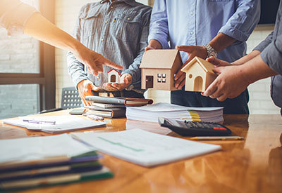 someone poining and picking a small model home