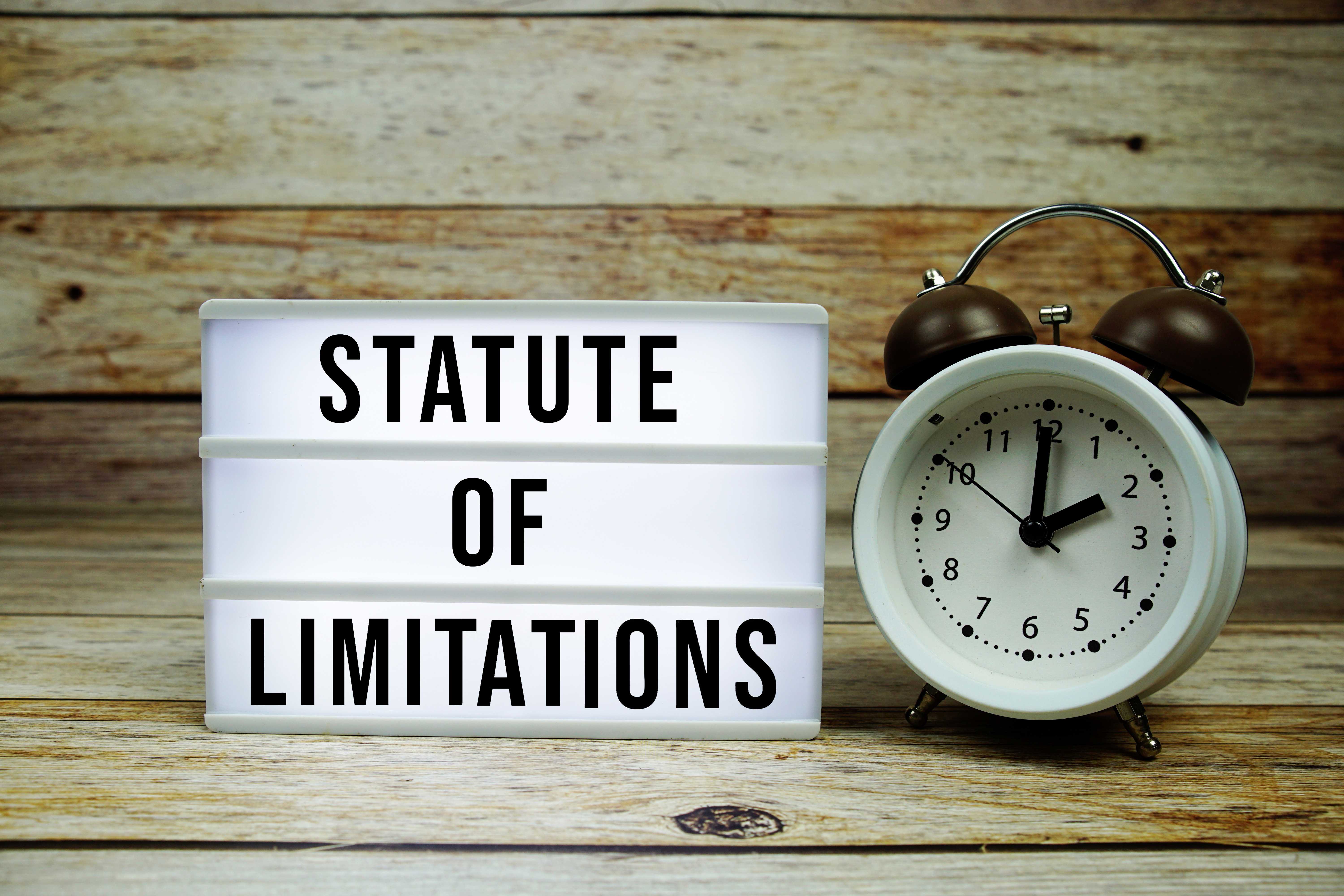 A lightbox displaying "STATUTE OF LIMITATIONS" next to an alarm clock, representing legal time constraints.