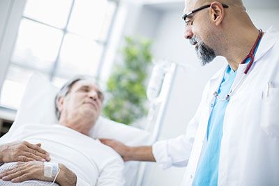 Senior patient in a hospital bed being visited by a doctor