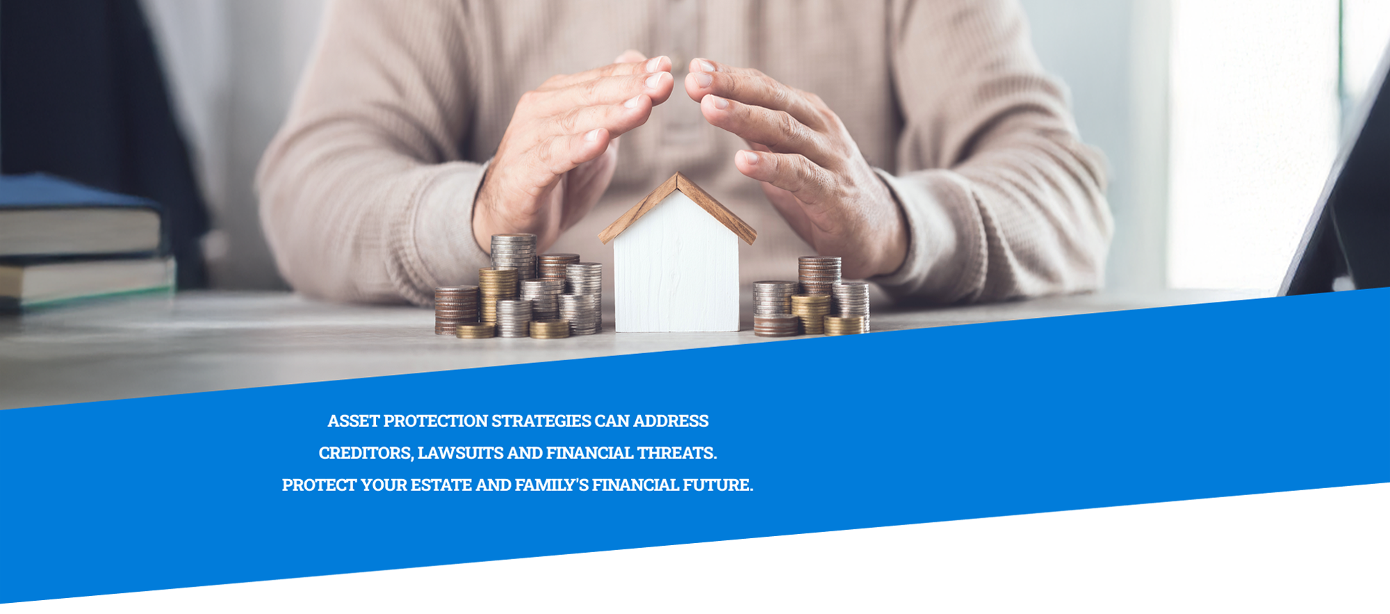 a pair of hands covering a model home and stacked coins on a table