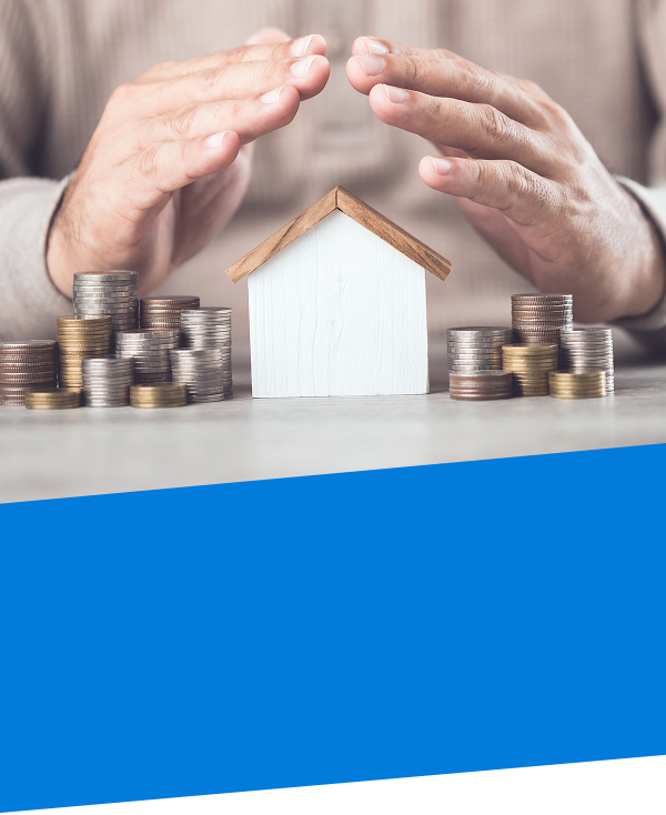 a pair of hands covering a model home and stacked coins on a table